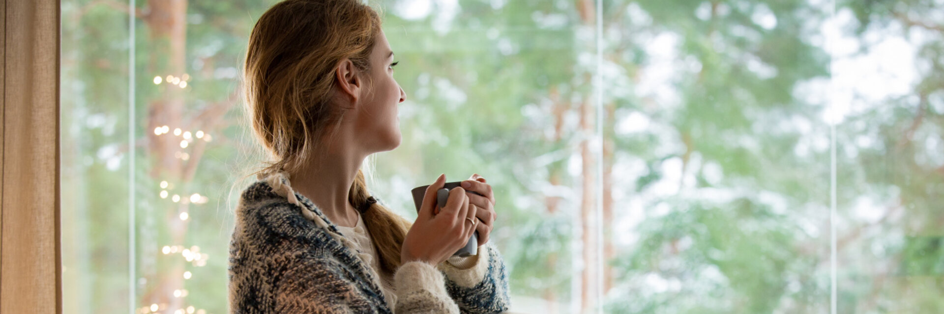 Woman sits in comfortable chair and looks out of the window,