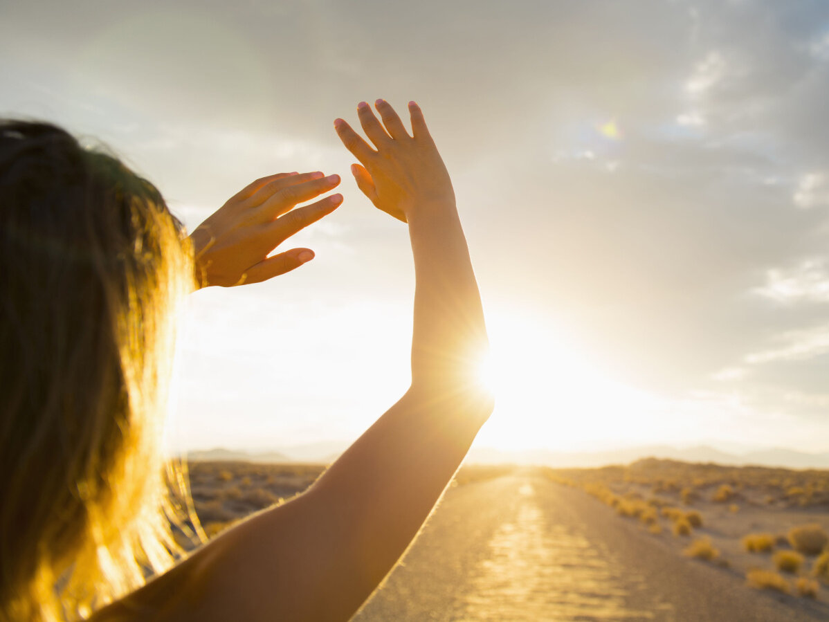 Hispanic woman shielding eyes from sun on remote road